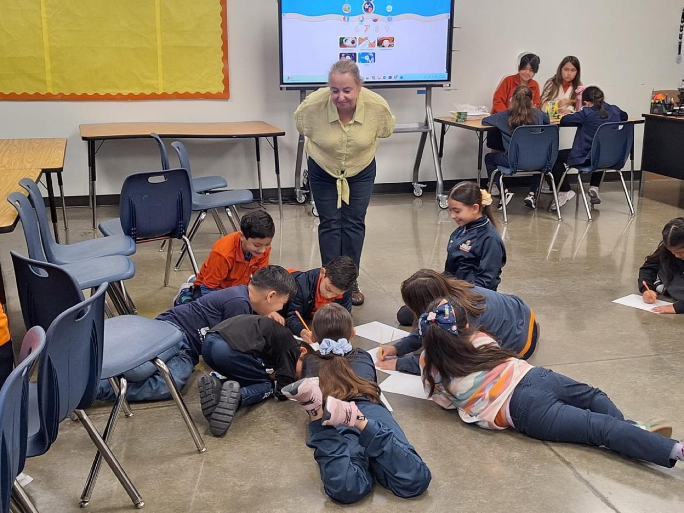 Children lying on a classroom floor, drawing together after a Hope Seed lesson