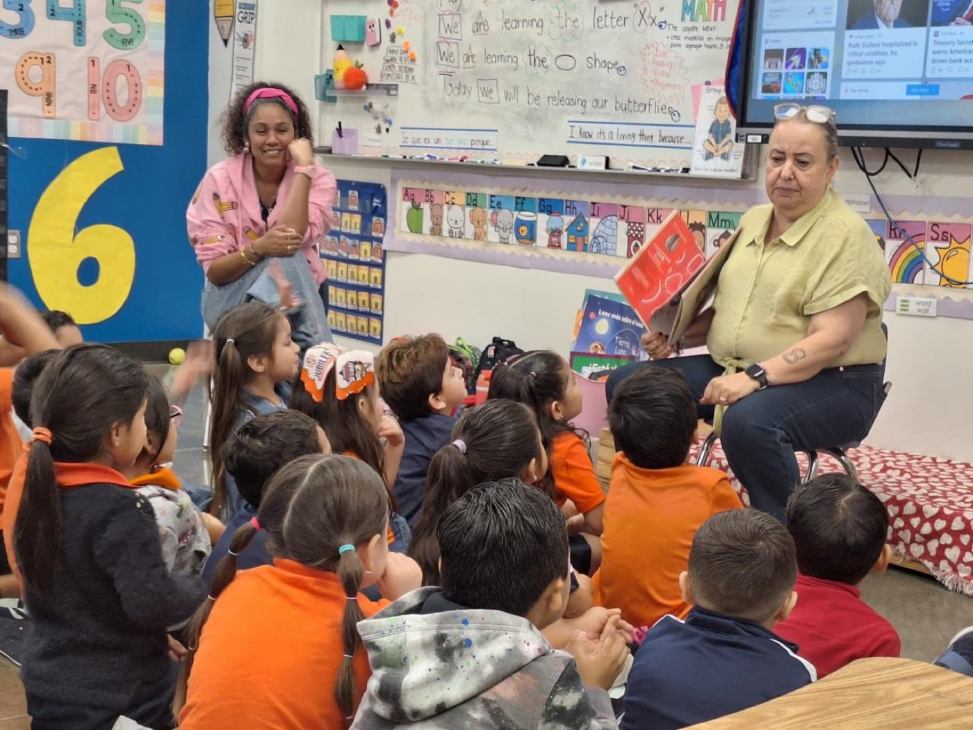 A teacher reading aloud to a seated group of young students